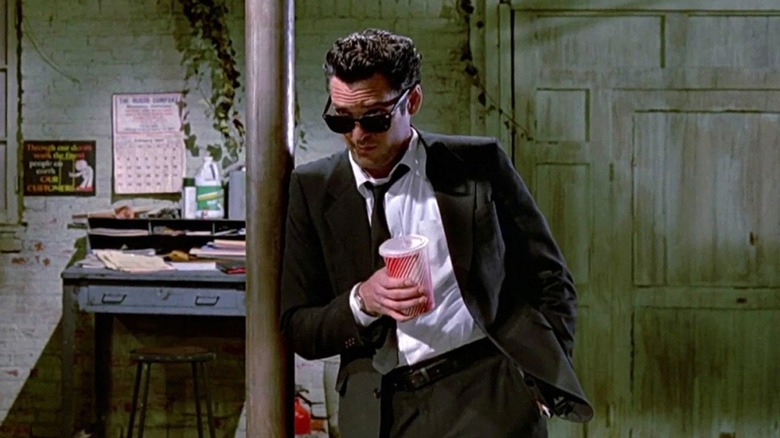 Vic Vega leans against a pole and holds a cup of soda in Reservoir Dogs (1992)