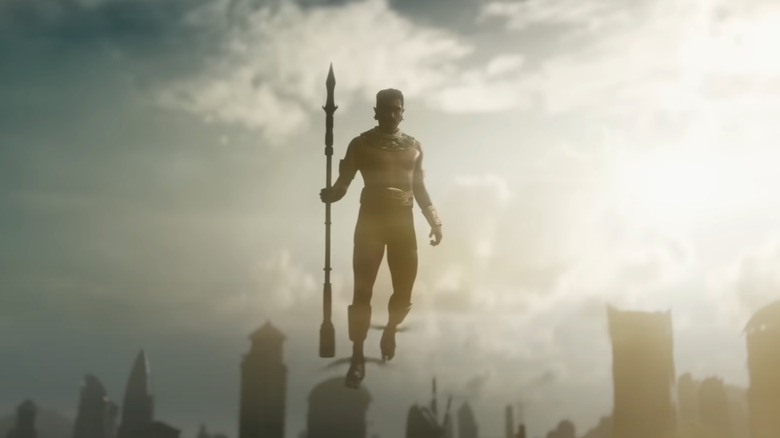 Namor flies above Wakanda while holding a spear 
