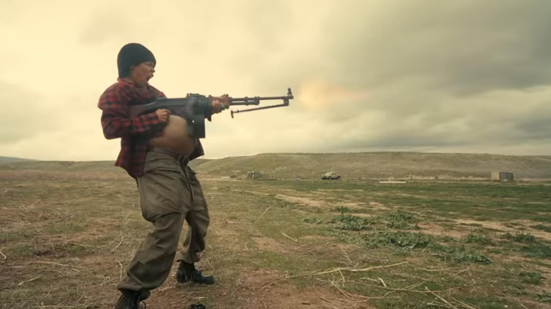 A pregnant Perfidia Beverly Hills firing off a gun in One Battle After Another ]