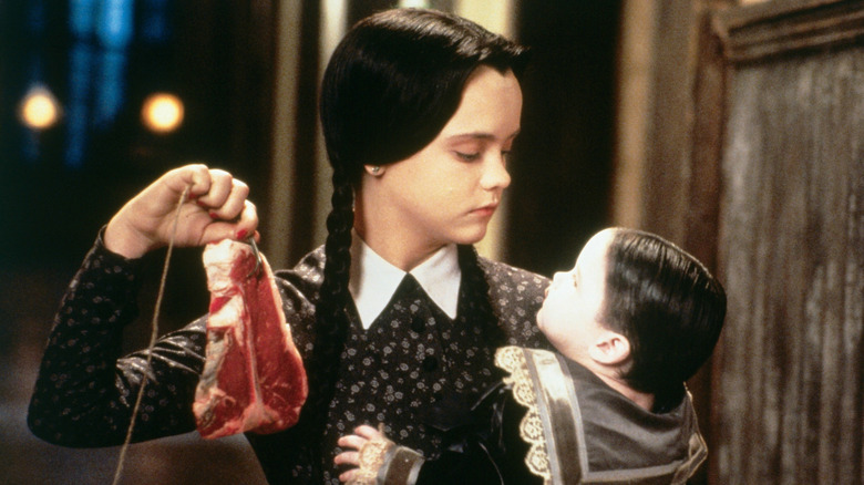 Wednesday holding Pubert and a raw steak