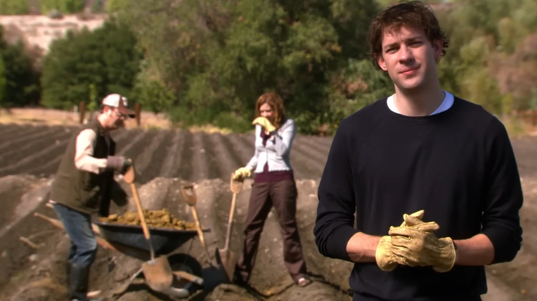 Jim Halpert (John Krasinski) talking to the camera in The Office with characters in the background