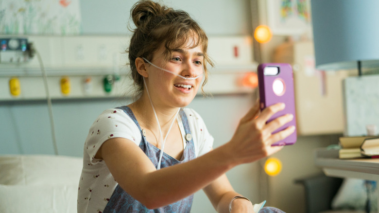 Stella Grant using her phone on her hospital bed