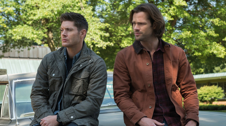 Dean and Sam sit on the hood of their car