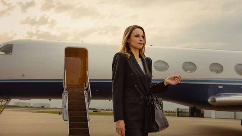 Kayla Wallace as Rebecca in front of a private jet on Landman