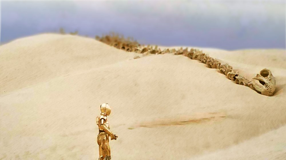 C-3PO stands in front of a krayt dragon skeleton