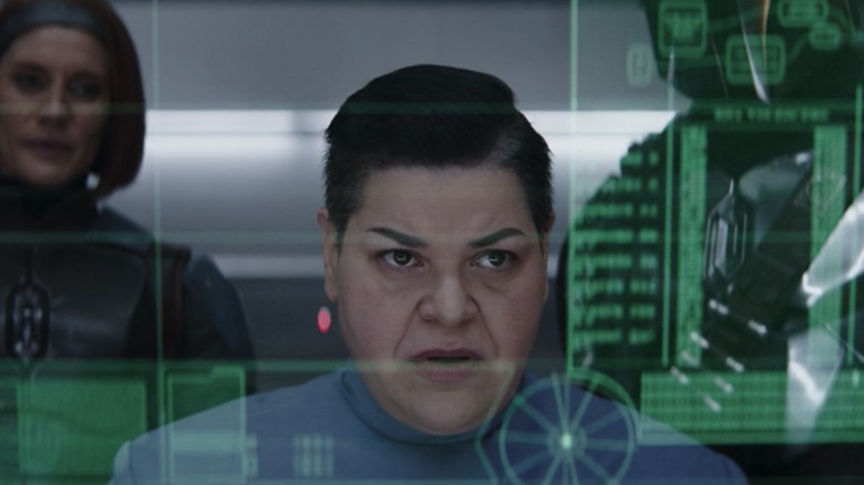 The lab technician poring over data while two mandalorians stand behind her