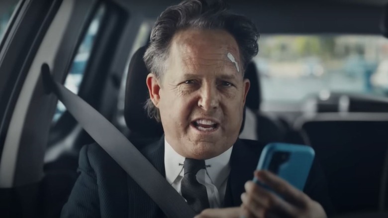 Mayhem holding a phone in a car