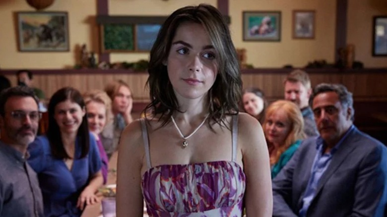 Bea standing in front of table with eight people seated around it in Wildflower