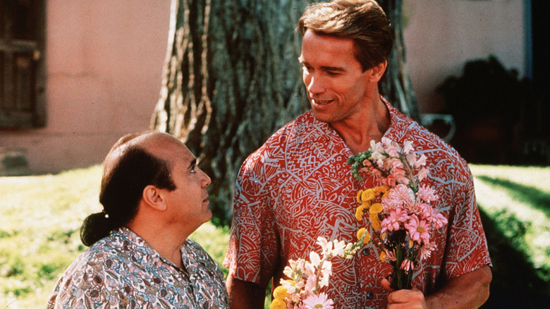 Vincent and Julius holding flowers in front of a tree in "Twins" (1988)