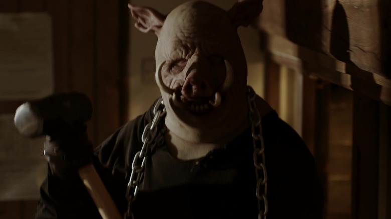Piglet with a chain around his neck holding a sledgehammer
