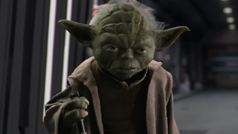 Yoda holding lightsaber hilt