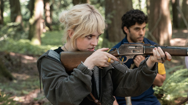 Natalie aiming rifle coach ben background