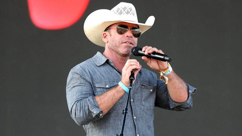 Taylor Sheridan wearing white cowboy hat holding microphone
