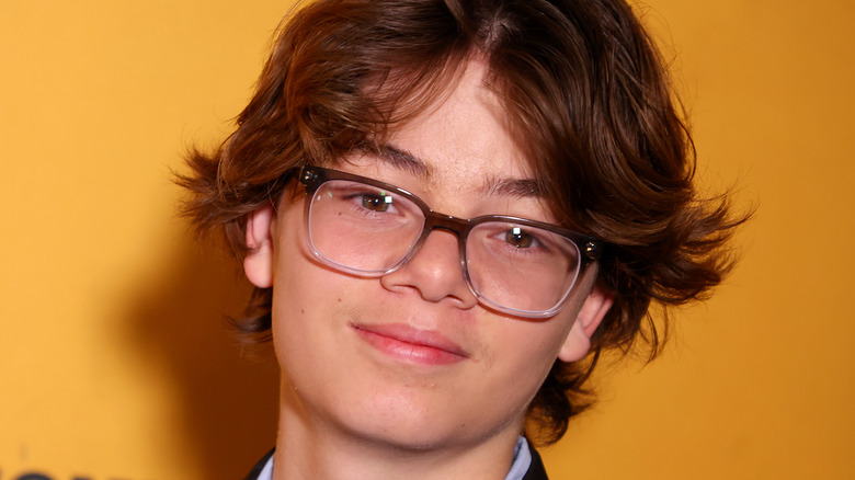 Brecken Merrill wearing glasses and smiling on red carpet