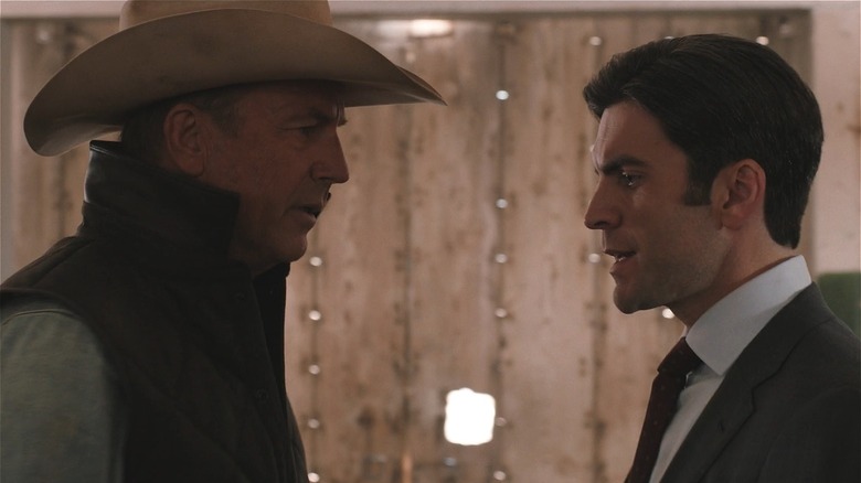Kevin Costner wearing cowboy hat staring down at Wes Bentley in a suit in Yellowstone