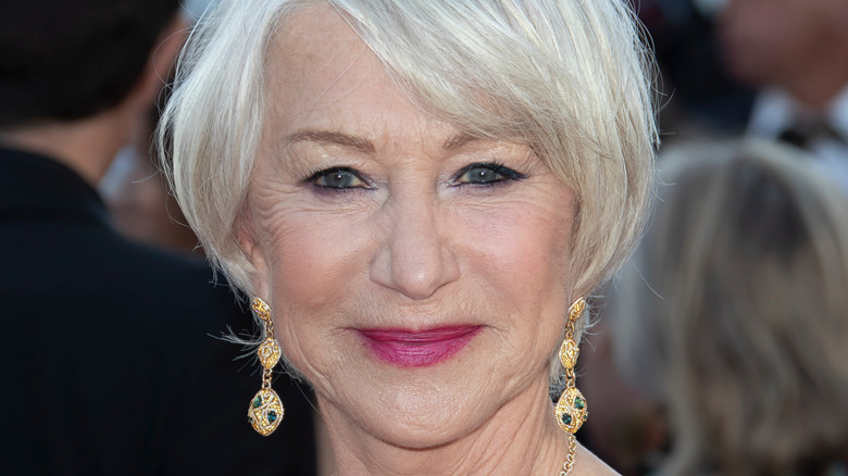 Helen Mirren smiling on red carpet wearing gold earrings