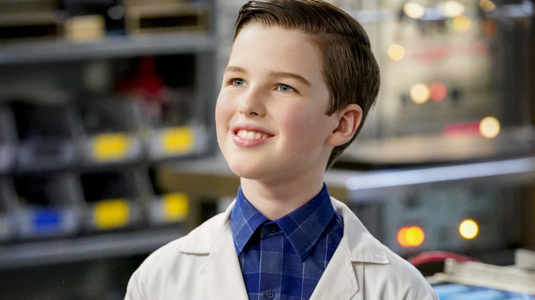 Young Sheldon smiling in a lab coat