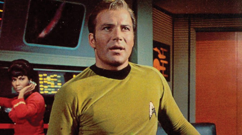 Captain Kirk giving orders while Uhura listens in the back in "Star Trek" (1966)