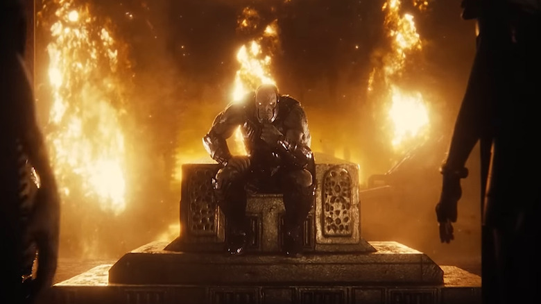 Darkseid sits on a throne, beset by fire